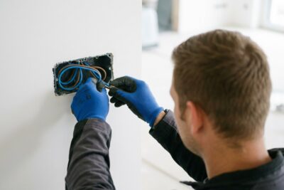 Elektriker in Coesfeld verkabelt eine Unterputzdose mit blauen und braunen Leitungen im Neubau