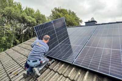 Elektrotechnik im Münsterland – Solarmodule fachgerecht auf dem Dach montiert Elektriker im Münsterland richtet ein Solarmodul auf einem Ziegeldach mit bestehender Photovoltaikanlage aus