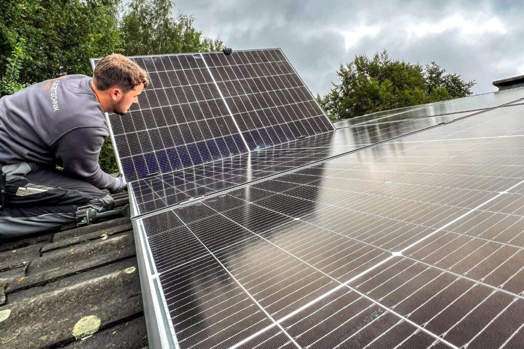 PV-Anlage nahe Dülmen – Solarmodule werden auf dem Hausdach montiert PV-Anlage nahe Dülmen im Münsterland – Elektriker montiert Solarmodule auf einem Hausdach und richtet ein Panel an der Montageschiene aus